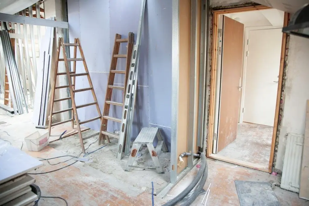 Werker op kamersteiger die veilig op hoogte werkt met valharnas en helm voor bescherming