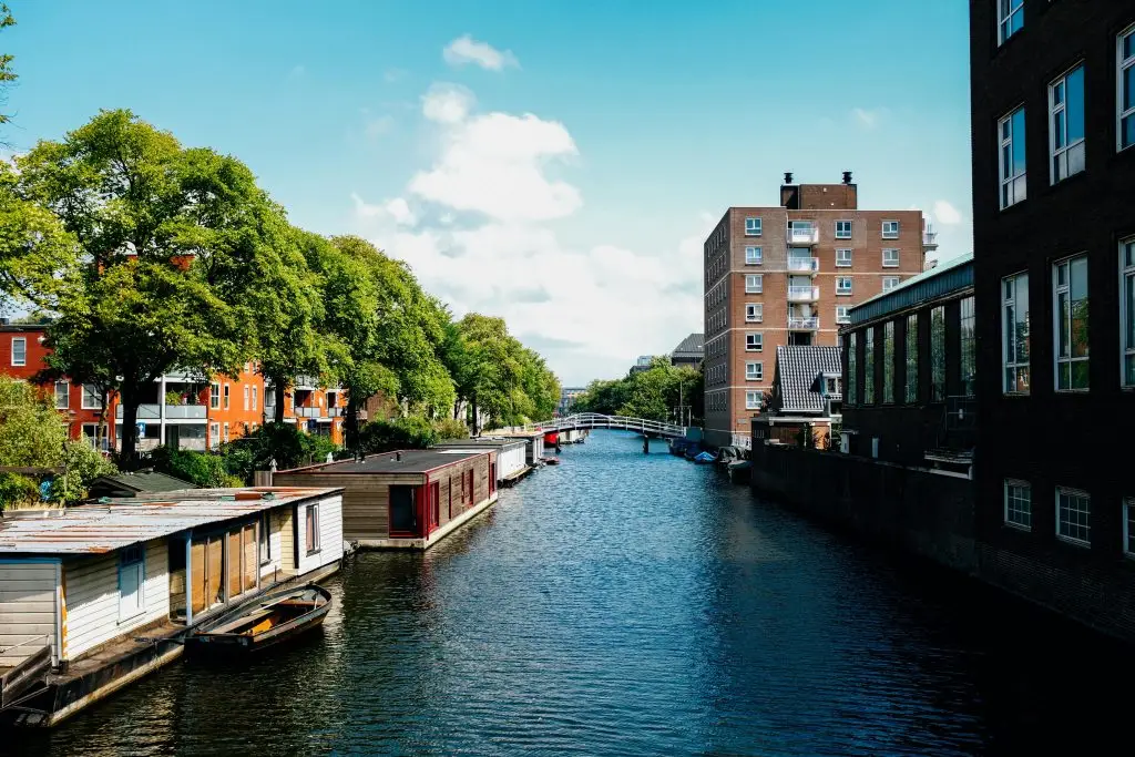 Student verhuist naar Amsterdam met fiets en spullen, staand in een straat met karakteristieke Nederlandse architectuur